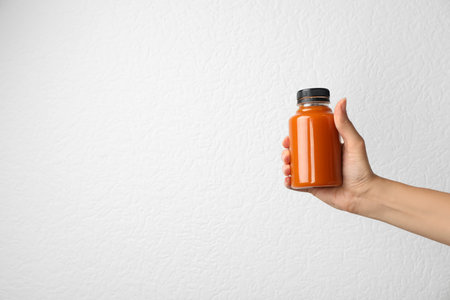 Woman holding bottle of carrot juice on gray background, closeup with space for textの写真素材