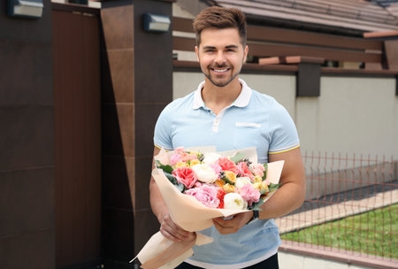 Young handsome man with beautiful flower bouquet outdoorsの写真素材