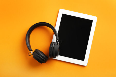 Stylish headphones and modern tablet on color background, flat lay. Space for textの写真素材