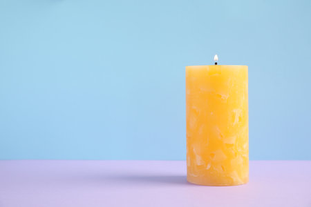 Alight wax candle on color background. Space for textの写真素材