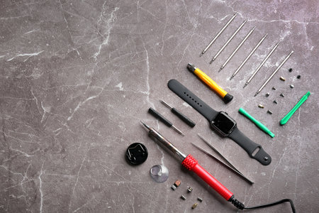 Flat lay composition with broken smart watch and tools on marble background, space for text. repair...