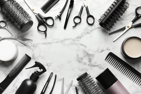 Frame made of scissors and other hairdresser's accessories on white marble background, flat lay. Space for textの写真素材