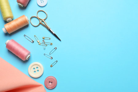 Flat lay composition with scissors and other sewing accessories on light blue background. Space for textの写真素材