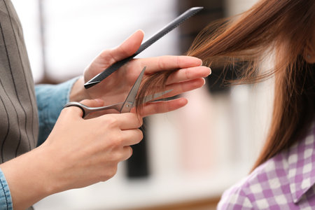 Barber making stylish haircut with professional scissors in beauty salon, closeupの写真素材