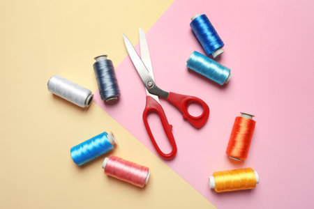 Bobbins of  sewing scissors on color background, flat lay