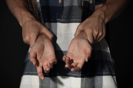 Man holding woman's hands on dark background, closeup. Stop sexual assaultの写真素材