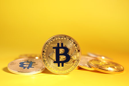 Shiny bitcoins on yellow background. digital currencyの写真素材