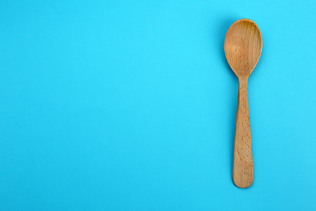 Clean empty wooden spoon on blue background, top view. Space for textの写真素材