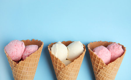 Delicious ice creams in wafer cones on blue background, flat lay. Space for textの写真素材