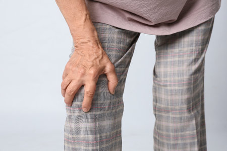Senior woman having knee problems on gray background, closeupの写真素材