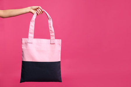 Young woman holding textile bag on pink background, closeupの写真素材