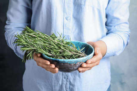 Young woman holding bowl of fresh rosemary, closeupの写真素材