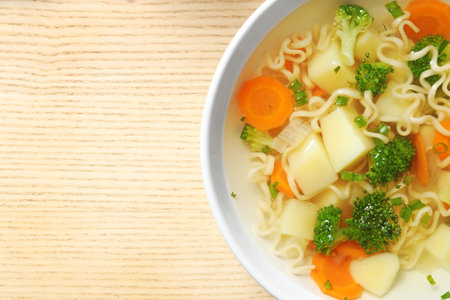 Bowl of fresh homemade vegetable soup on wooden background, top view. Space for textの写真素材