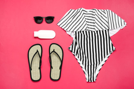 Flat lay composition with striped swimsuit and beach accessories on coral backgroundの写真素材