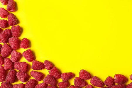 Frame made with delicious ripe raspberries on yellow background. Space for textの写真素材