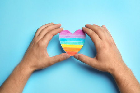 Man with rainbow heart on blue background, top view. gay symbolの写真素材