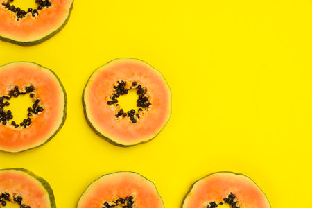 Flat lay composition with slices of papaya on yellow background, space for textの写真素材