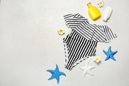 Flat lay composition with striped swimsuit and beach accessories on light stone background. Space for textの写真素材