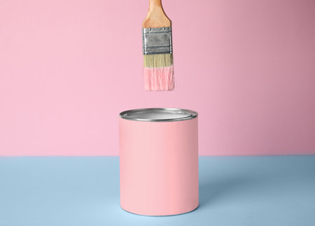 Brush over can of pink paint on blue tableの写真素材