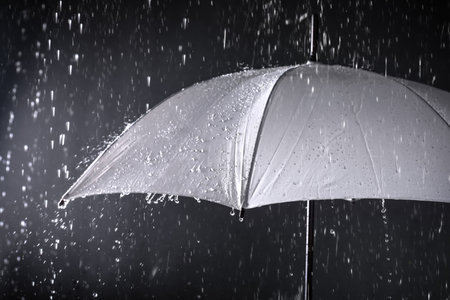 White umbrella under rain on dark backgroundの写真素材