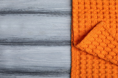 Orange kitchen towel on wooden background, top view. Space for text