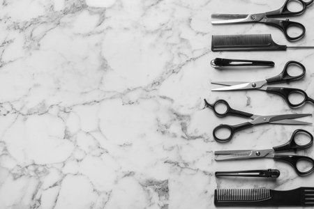 Flat lay composition with scissors and other hairdresser's accessories on white marble background. Space for textの写真素材