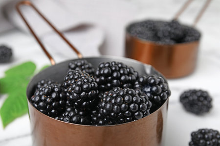 Metal saucepan with tasty ripe blackberries on table, closeupの写真素材