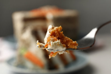 Fork with piece of carrot cake against blurred dessert, closeupの写真素材