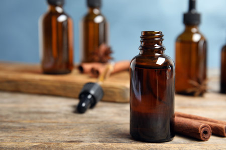Bottle of essential oil and cinnamon sticks on wooden table against blue background. Space for textの写真素材
