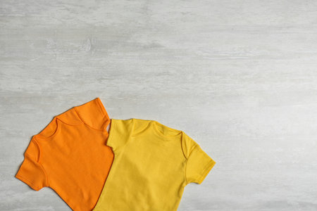 Different baby bodysuits on wooden background, top view. Space for textの写真素材