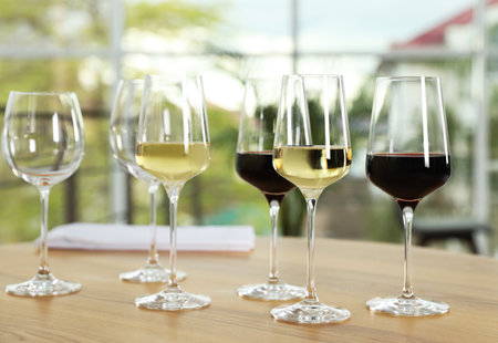 Glasses with different wines on table against blurred backgroundの写真素材