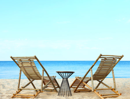 Empty wooden sunbeds and beach accessories on sandy shoreの写真素材