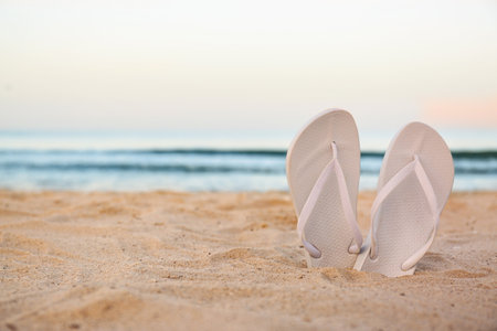 White flip flops on sand near sea, space for text. beach accessoriesの写真素材
