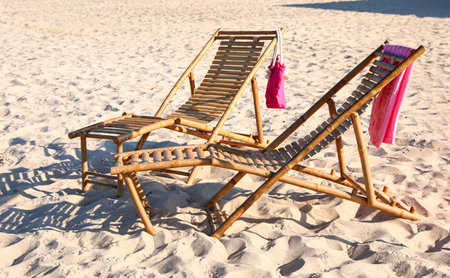 Empty wooden sunbeds and beach accessories on sandy shoreの写真素材