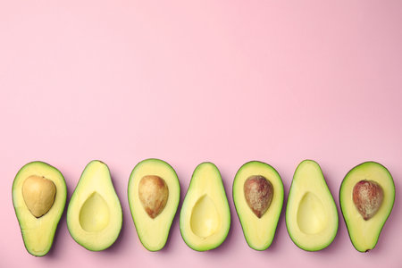 Cut fresh ripe avocados on pink background, flat lay with space for textの写真素材