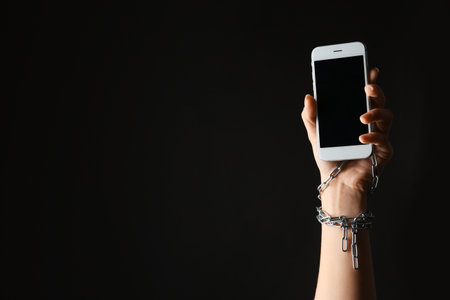 Woman chained to smartphone on black background, closeup with space for text. Loneliness conceptの写真素材