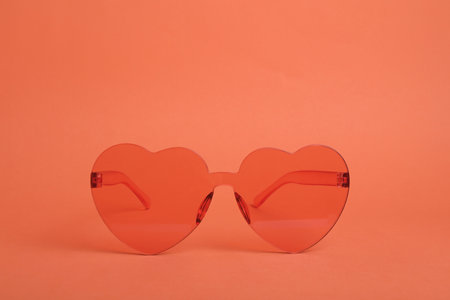 Heart shaped coral sunglasses on orange backgroundの写真素材