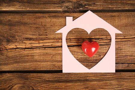 Paper house and red heart on wooden background, flat lay. Space for textの写真素材