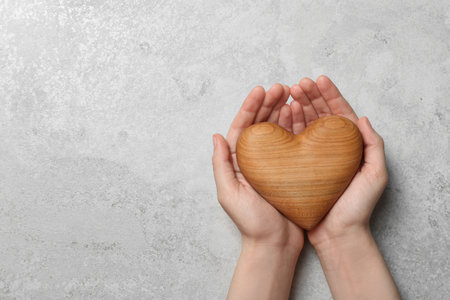 Woman holding heart on gray stone background, top view with space for text. Donation conceptの写真素材