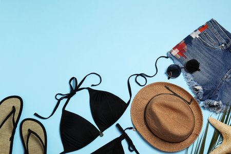 Flat lay composition with stylish beach accessories on light blue background, space for textの写真素材