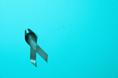 Teal awareness ribbon on light blue background, top view with space for text. Symbol of social and medical issuesの写真素材