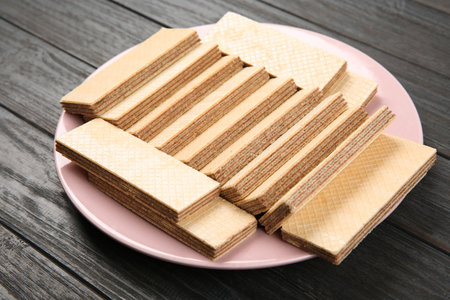 Plate with delicious crispy wafers on wooden tableの写真素材