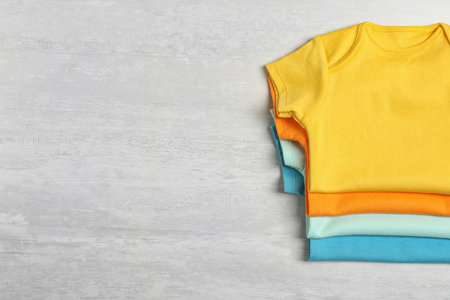 Different baby bodysuits on wooden background, top view. Space for textの写真素材