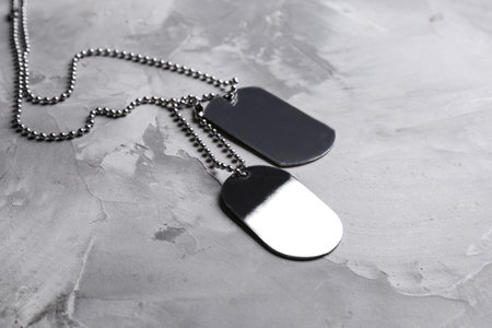 Blank military ID tags on gray stone surface, space for textの写真素材