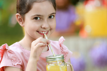 Cute little girl drinking natural lemonade in park, closeup with space for text. Summer Refreshing Beverageの写真素材