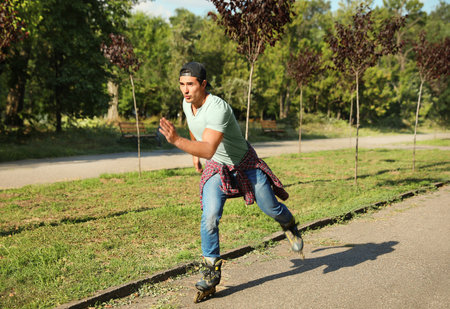 Handsome young man roller skating in park