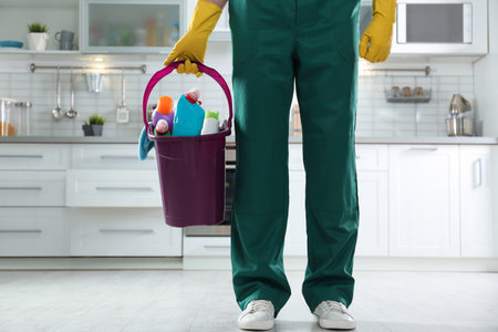 Janitor with bucket of detergents in kitchen, closeup. cleaning serviceの写真素材