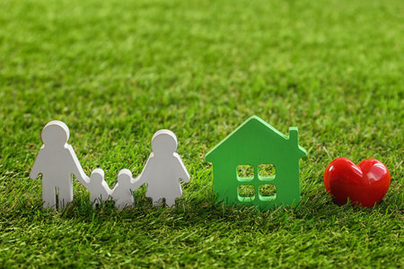 Figures of family, red heart and house on green grassの写真素材