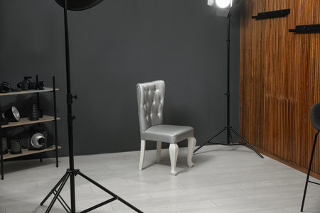 Stylish silver chair and professional equipment in photographer's studio