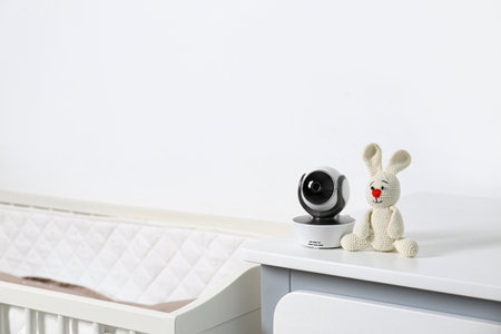 Baby camera with toy on chest of drawers near crib in room, space for text. Video nannyの写真素材
